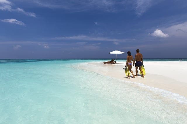 A couple in bathing suits walking along the beach